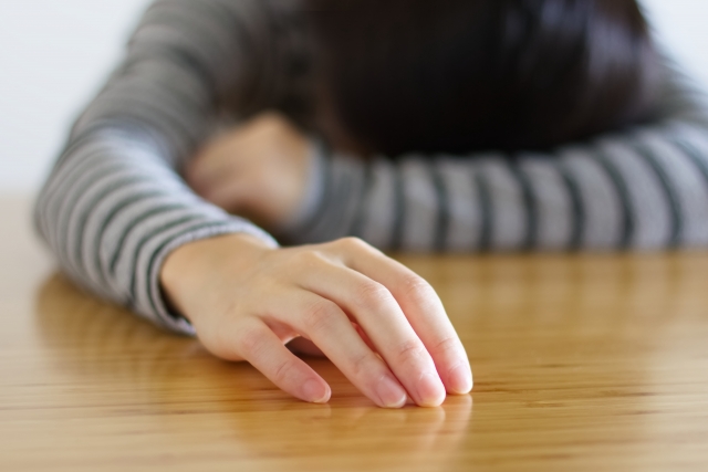 机の上でぐったりとする女性