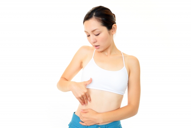 おなか周りのサイズと脂肪の付き具合を確認する女性