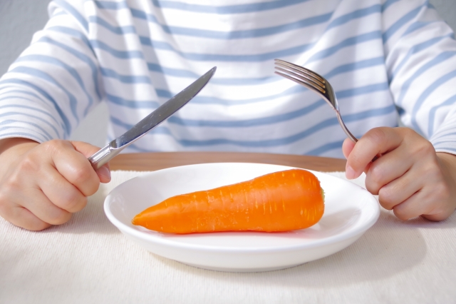 ダイエットのために、極端な食事制限を行う女性（野菜だけで食事を済ませようとしているイメージ）