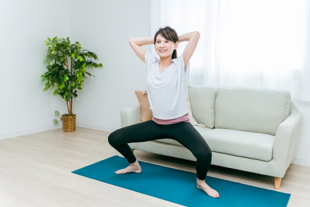 屋内で、ダイエットなどにも効果的な、下半身の筋力トレーニング（スクワット）を行う女性