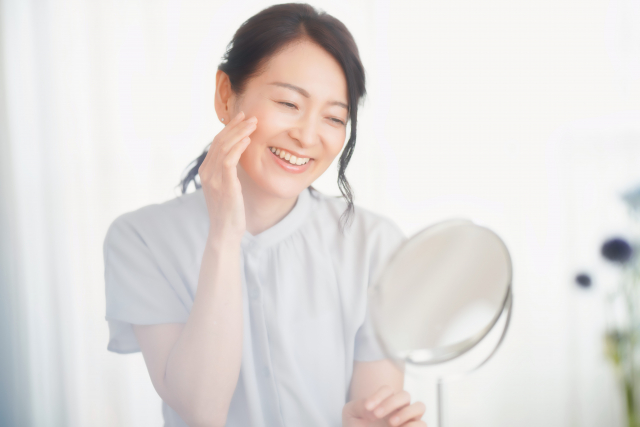 鏡で肌の調子を確認している女性（顔色の状態、血行、しみ、しわ、たるみなど）