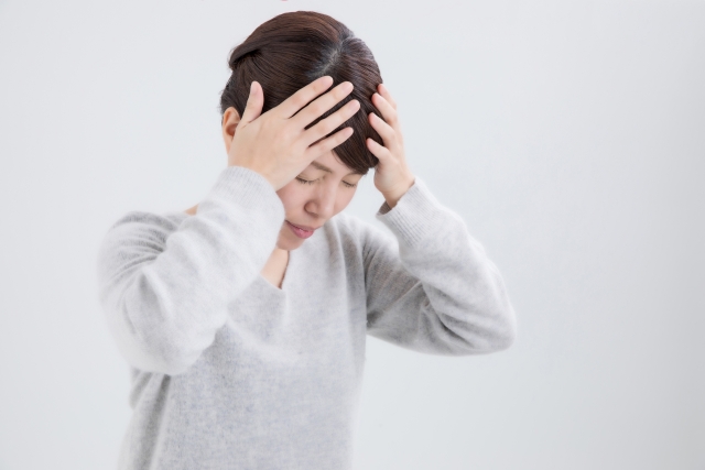 頭を抱えている女性（頭痛、ストレス、悩み、自律神経の乱れなど）