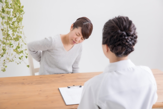 病院で医師に診察を受ける女性（腰痛）
