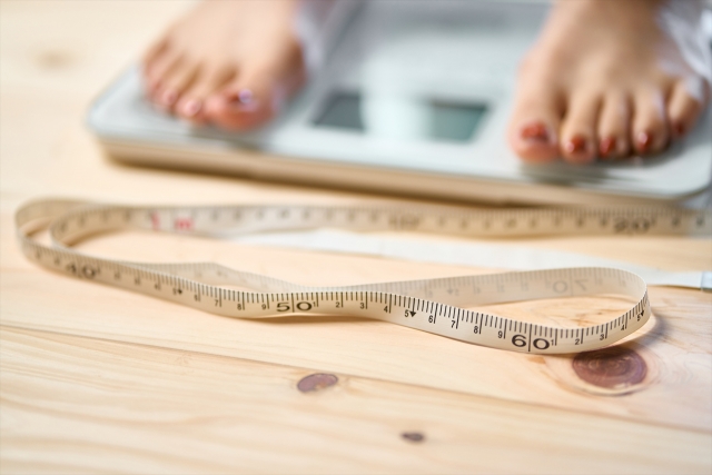 ダイエットのイメージ（体重計/体組成計に乗り、計測をする女性）