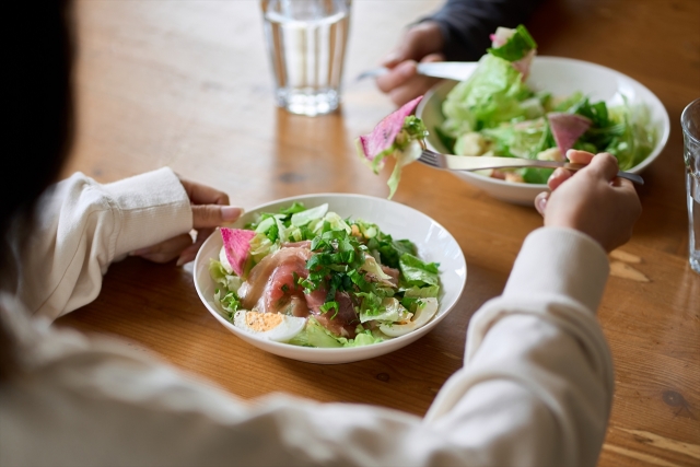 栄養バランスを考えて、野菜サラダを食べる女性